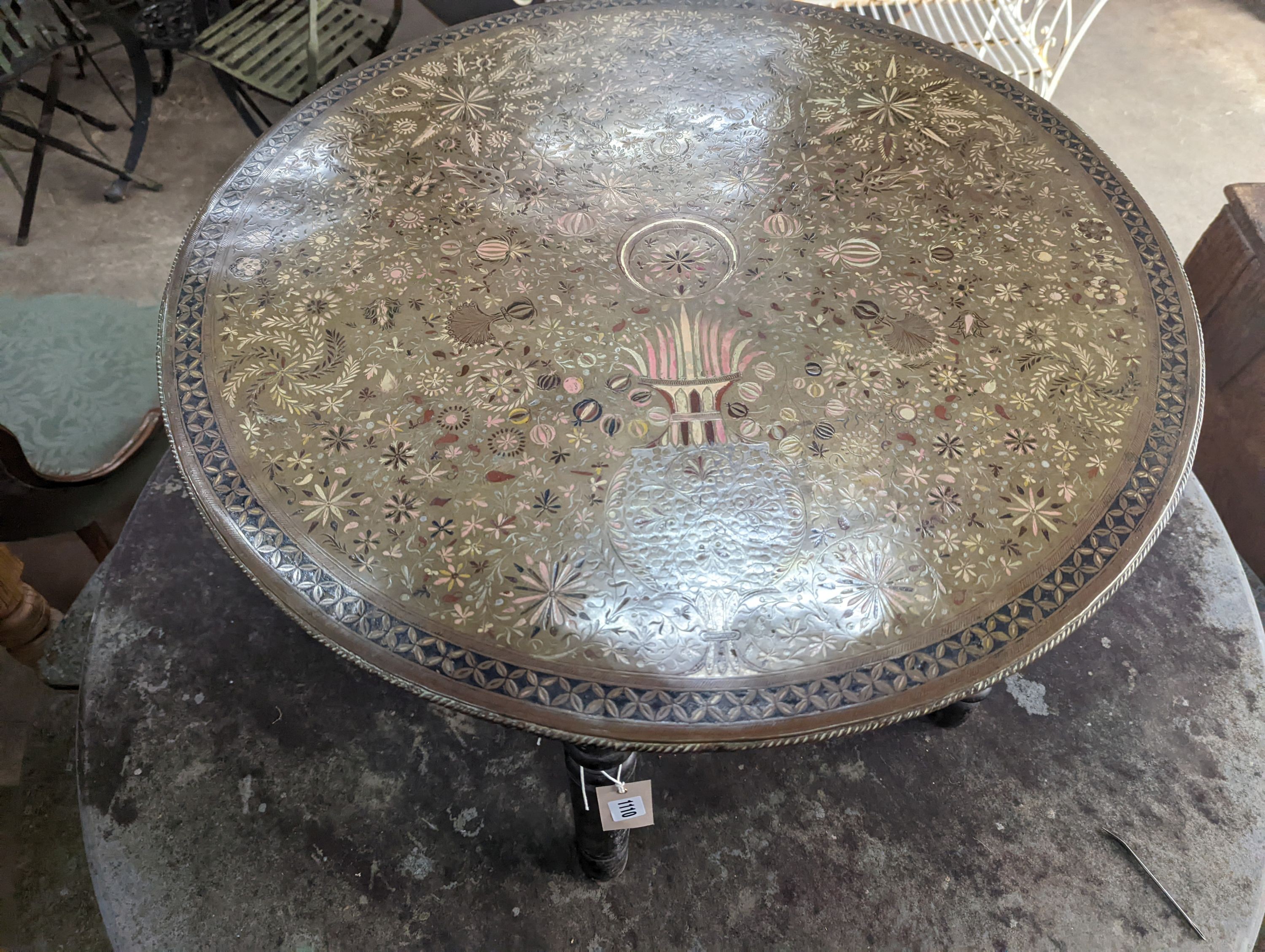 A late 19th century Indian brass and polychrome foliate enamel decorated circular topped occasional table, raised on a turned folding stand, diameter 77cm, height 48cm